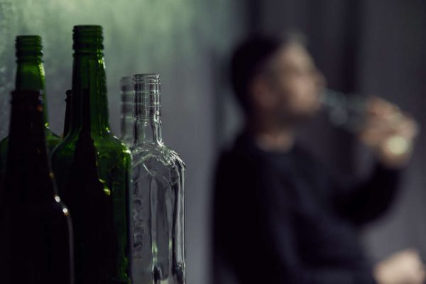 Empty,Bottles,Of,Alcohol,With,Drinking,Man